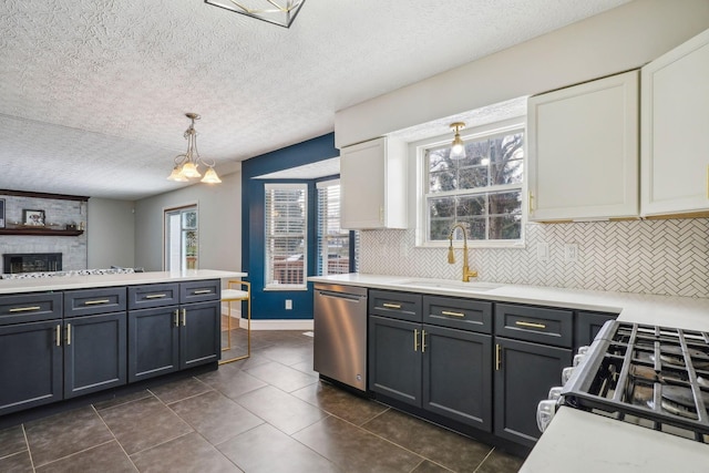 kitchen featuring pendant lighting, white cabinetry, sink, stainless steel dishwasher, and gas stove