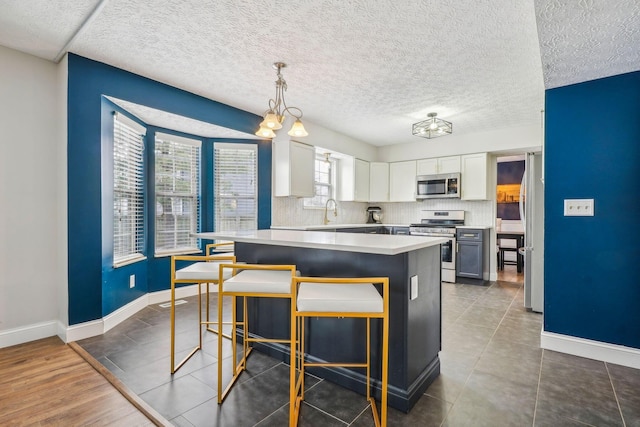 kitchen with pendant lighting, white cabinetry, a kitchen breakfast bar, and appliances with stainless steel finishes