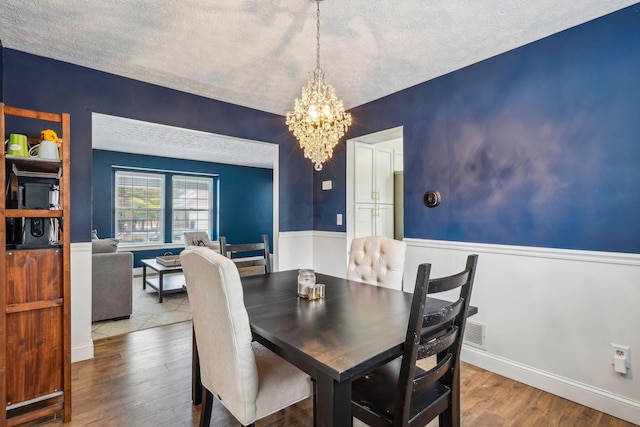 dining room featuring hardwood / wood-style flooring, a textured ceiling, and an inviting chandelier