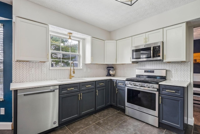 kitchen featuring appliances with stainless steel finishes, white cabinetry, sink, decorative backsplash, and a textured ceiling