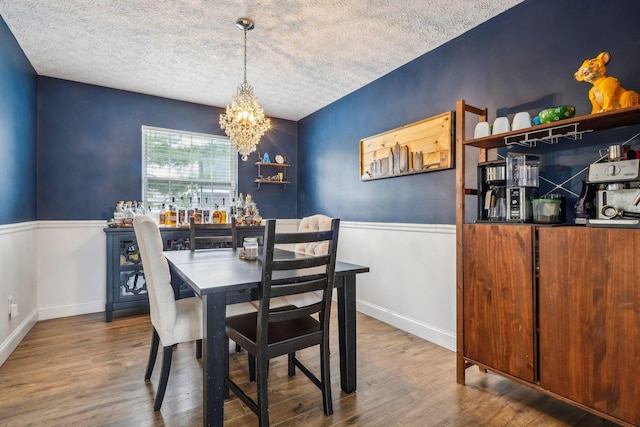 dining space featuring an inviting chandelier, hardwood / wood-style floors, and a textured ceiling