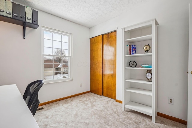 office space featuring light carpet, built in features, and a textured ceiling