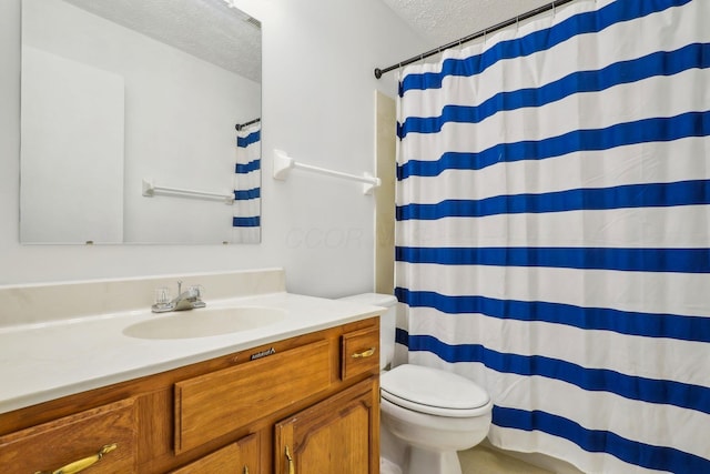 bathroom with vanity, toilet, curtained shower, and a textured ceiling