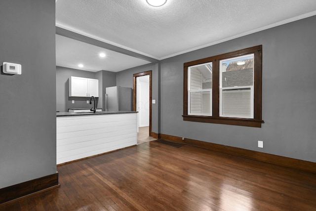 unfurnished living room with ornamental molding, dark hardwood / wood-style flooring, sink, and a textured ceiling