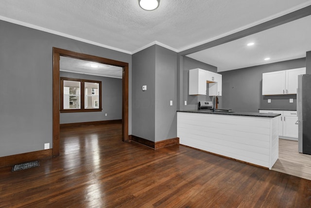 kitchen with crown molding, stainless steel fridge, white cabinetry, dark hardwood / wood-style floors, and a textured ceiling