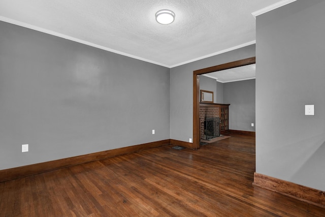 unfurnished living room with ornamental molding, a brick fireplace, a textured ceiling, and dark hardwood / wood-style flooring