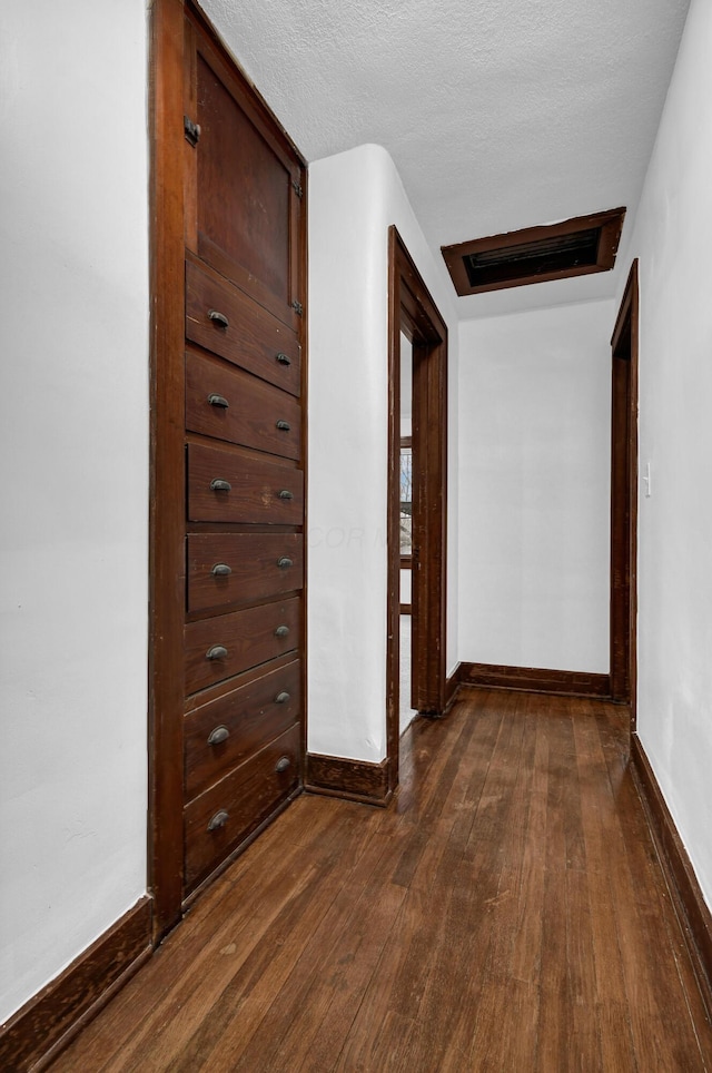 hall with dark wood-type flooring and a textured ceiling