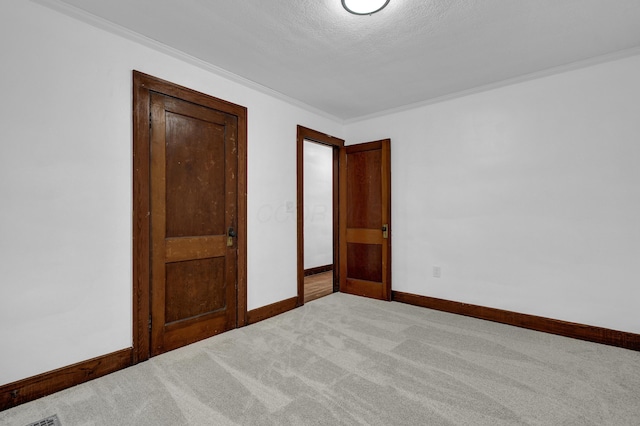 unfurnished bedroom with crown molding, light carpet, and a textured ceiling