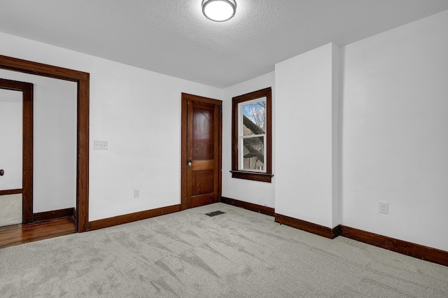 carpeted empty room with a textured ceiling