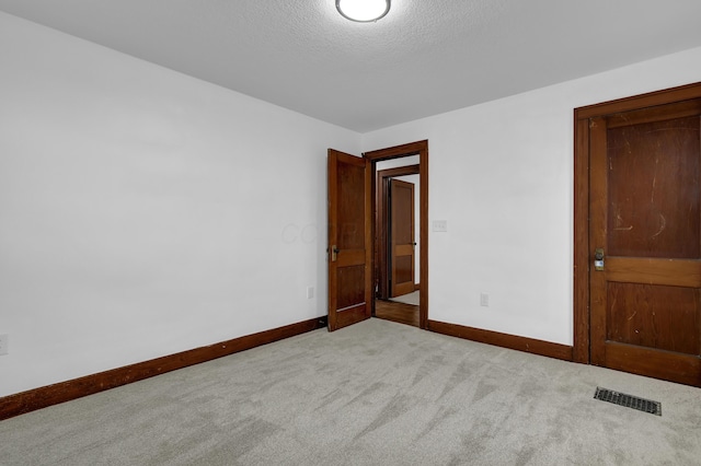 carpeted empty room featuring a textured ceiling