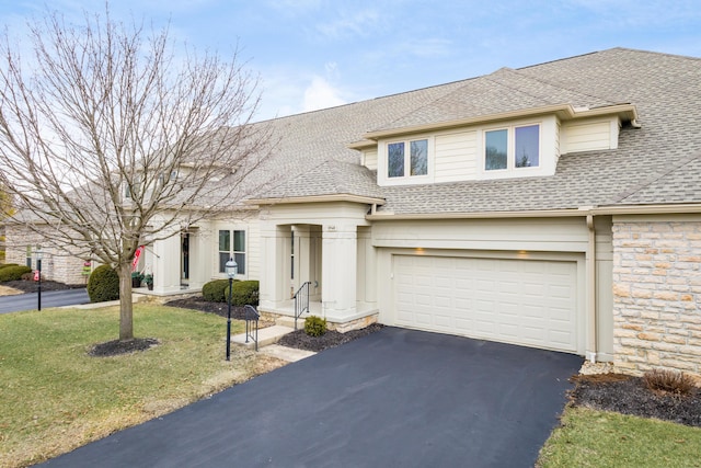 view of front of home featuring aphalt driveway, an attached garage, stone siding, roof with shingles, and a front yard