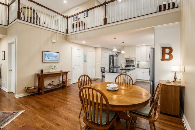 dining area featuring a towering ceiling, baseboards, and wood finished floors