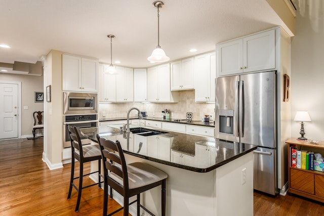 kitchen with dark wood-style flooring, a sink, white cabinetry, appliances with stainless steel finishes, and tasteful backsplash