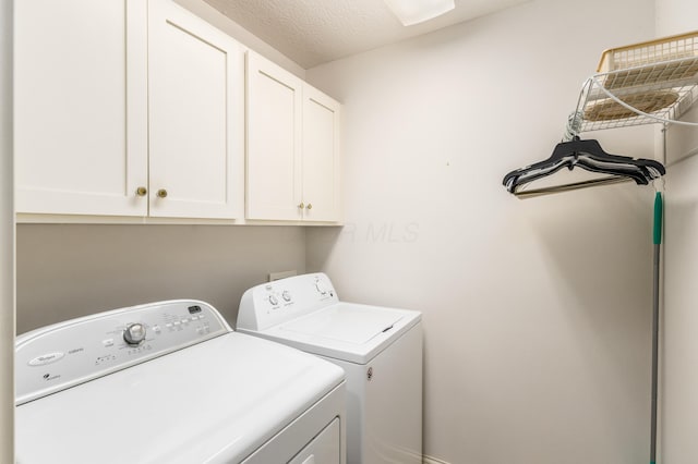 washroom with cabinet space, washing machine and dryer, and a textured ceiling