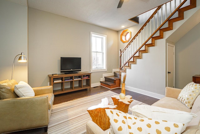 living area with baseboards, a ceiling fan, stairway, wood finished floors, and a textured ceiling