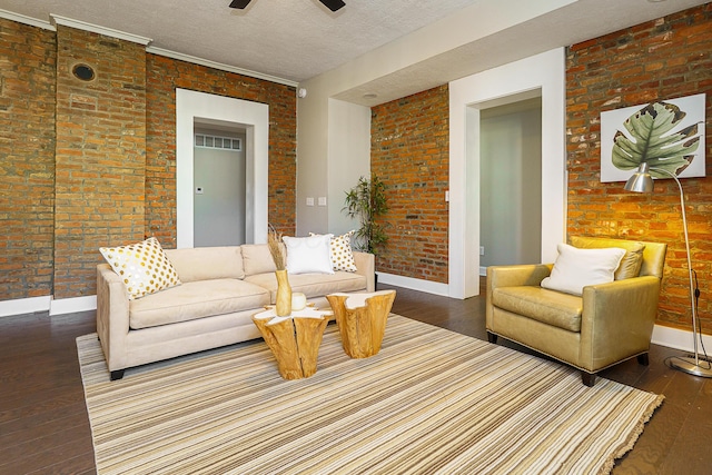 living area with a textured ceiling, brick wall, hardwood / wood-style floors, and visible vents