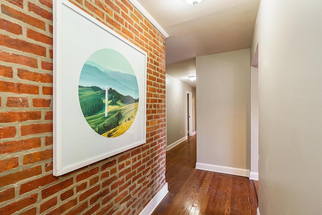 hallway with baseboards, dark wood finished floors, and brick wall