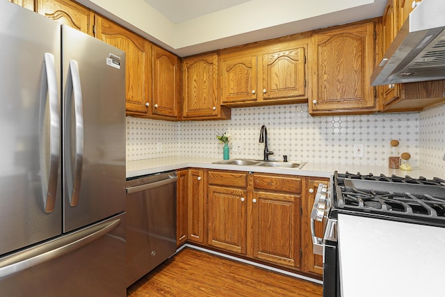 kitchen featuring brown cabinetry, extractor fan, stainless steel appliances, light countertops, and a sink