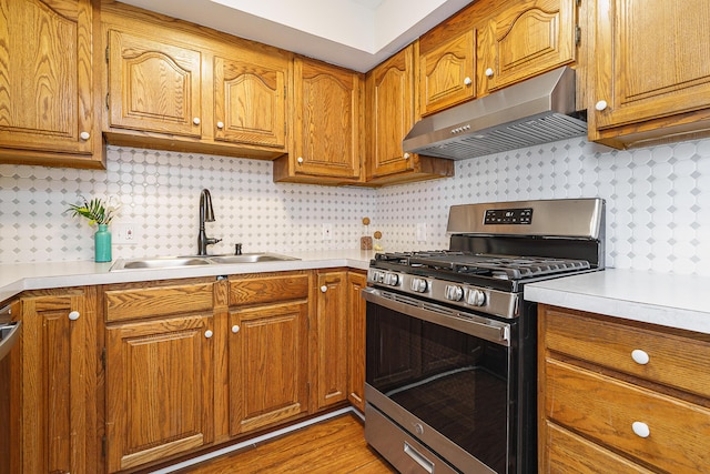 kitchen featuring a sink, light countertops, stainless steel gas range, range hood, and brown cabinetry