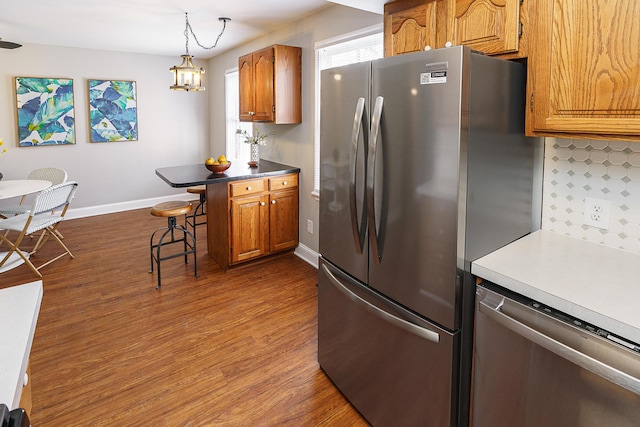 kitchen with stainless steel appliances, pendant lighting, brown cabinetry, and a kitchen breakfast bar