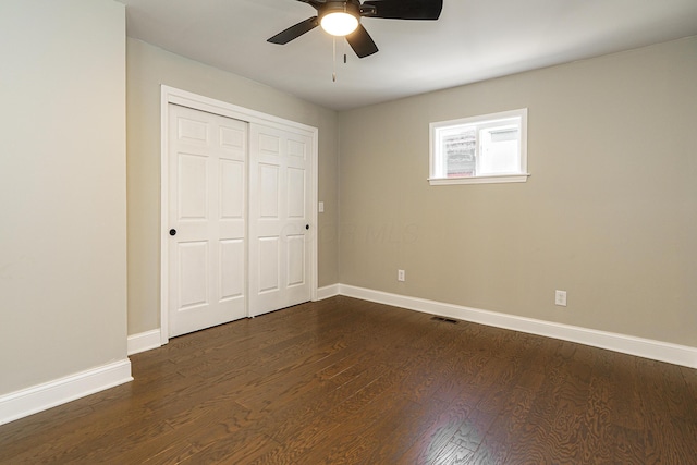 unfurnished bedroom featuring visible vents, a closet, baseboards, and dark wood-style flooring