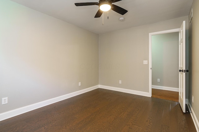 empty room featuring dark wood-type flooring, visible vents, ceiling fan, and baseboards