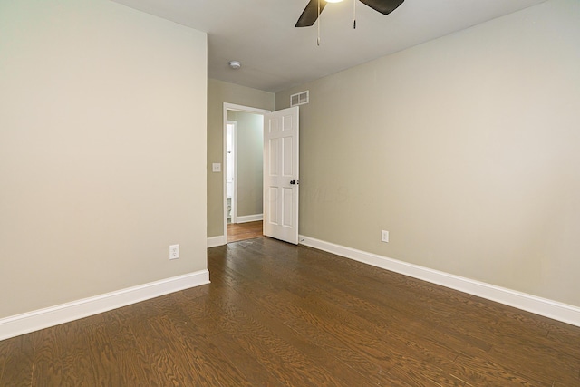 empty room with dark wood-type flooring, visible vents, ceiling fan, and baseboards