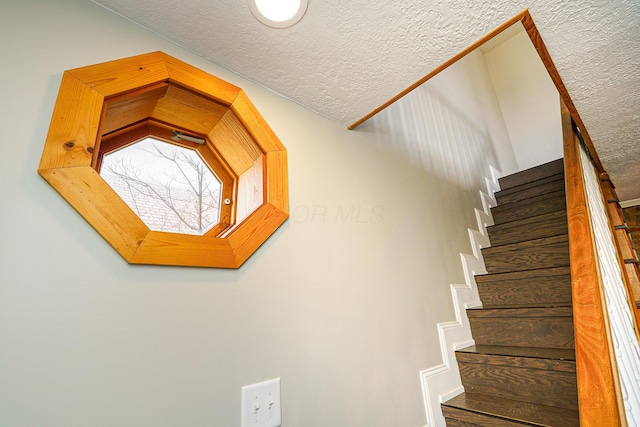 stairs featuring a textured ceiling and wood finished floors