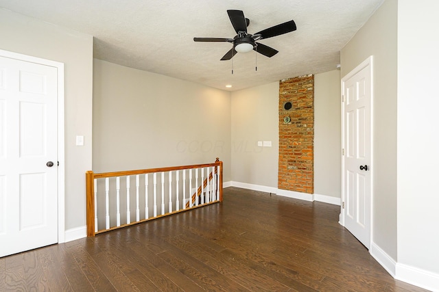 unfurnished room featuring dark wood-style floors, a textured ceiling, and baseboards