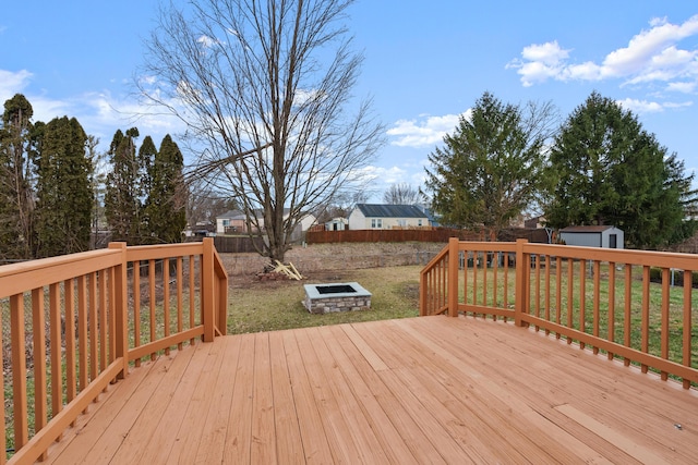 wooden deck with a storage shed, an outdoor fire pit, and a yard