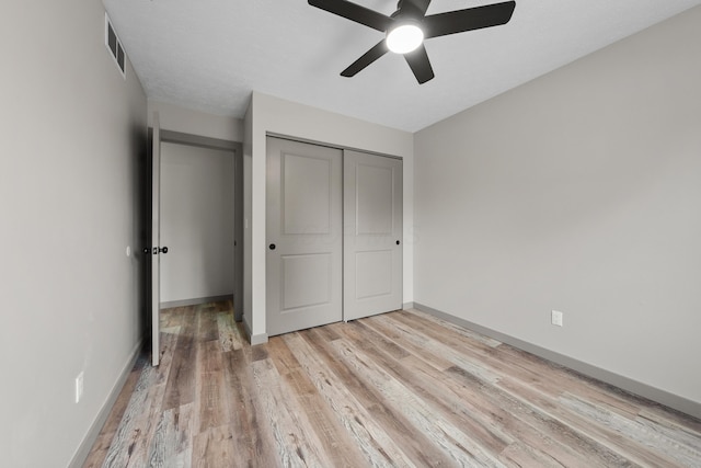 unfurnished bedroom with light hardwood / wood-style flooring, a closet, and ceiling fan