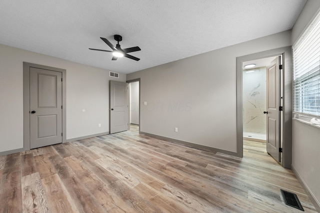 unfurnished bedroom with ensuite bathroom, a textured ceiling, and light hardwood / wood-style floors