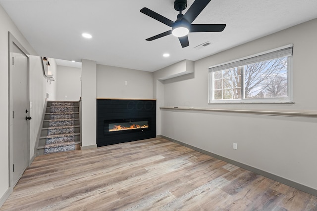 unfurnished living room featuring ceiling fan and light hardwood / wood-style floors