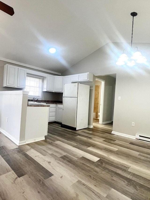 kitchen with vaulted ceiling, decorative light fixtures, white cabinets, dark hardwood / wood-style flooring, and white fridge