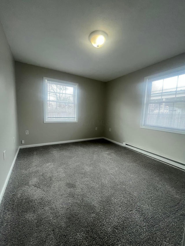 carpeted spare room featuring a baseboard heating unit