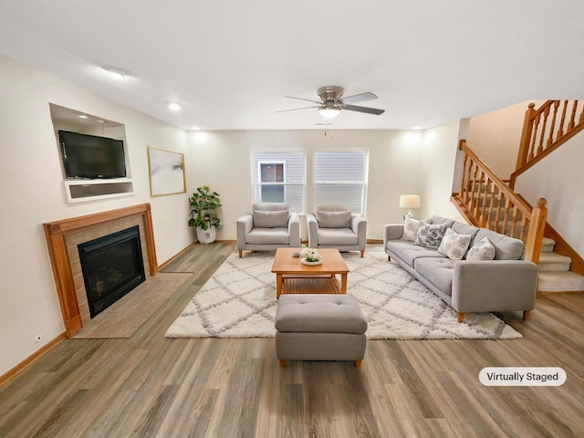 living room with hardwood / wood-style flooring, ceiling fan, and a tile fireplace