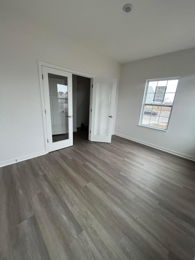 unfurnished bedroom with dark wood-style floors, french doors, and baseboards