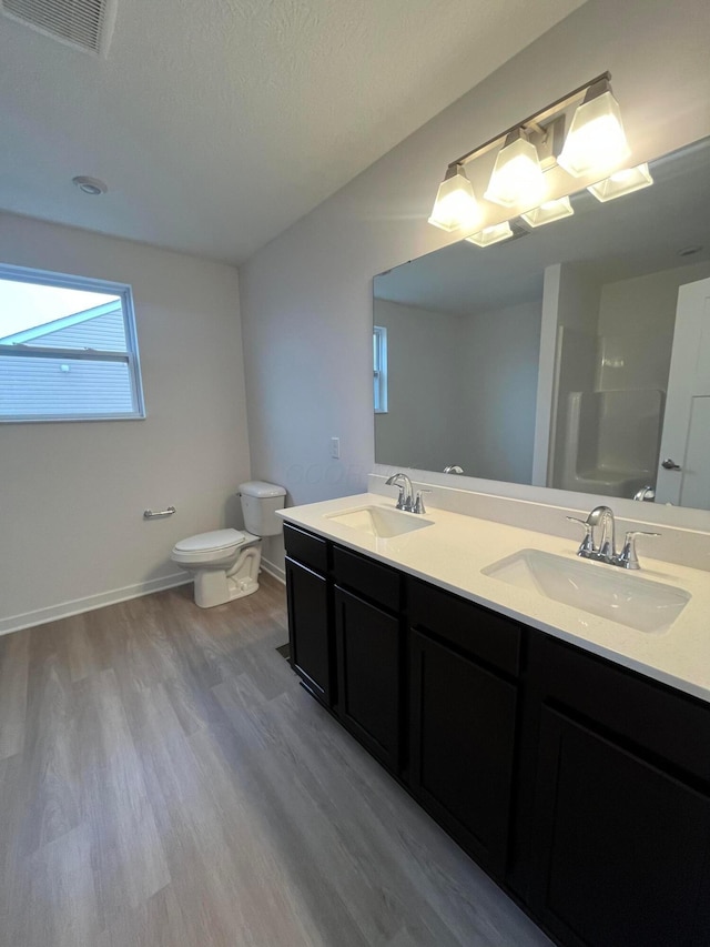 bathroom featuring vanity, wood-type flooring, toilet, and walk in shower