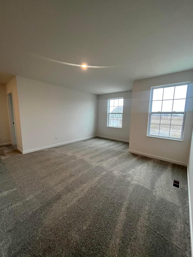 carpeted spare room featuring visible vents and baseboards