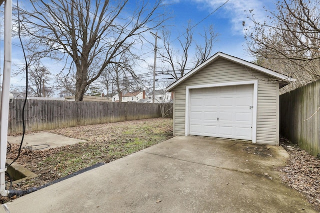 detached garage featuring concrete driveway and fence