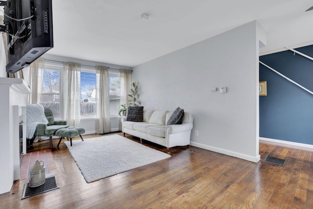 living area with hardwood / wood-style flooring, visible vents, and baseboards