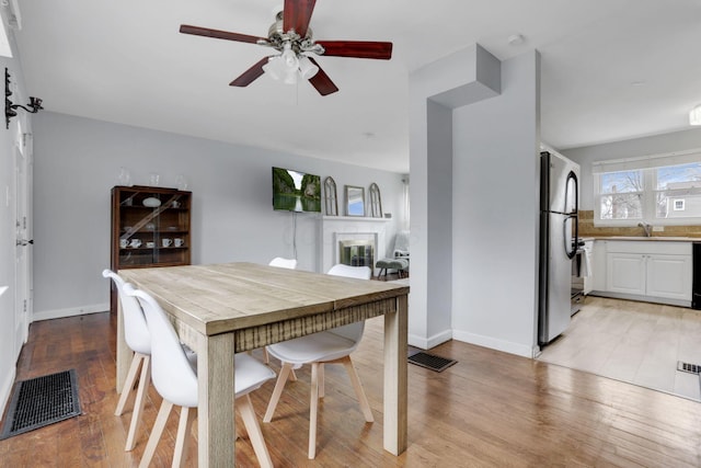 dining space featuring light wood finished floors, a fireplace, and visible vents