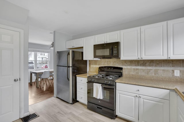 kitchen featuring black appliances, tasteful backsplash, visible vents, and white cabinets