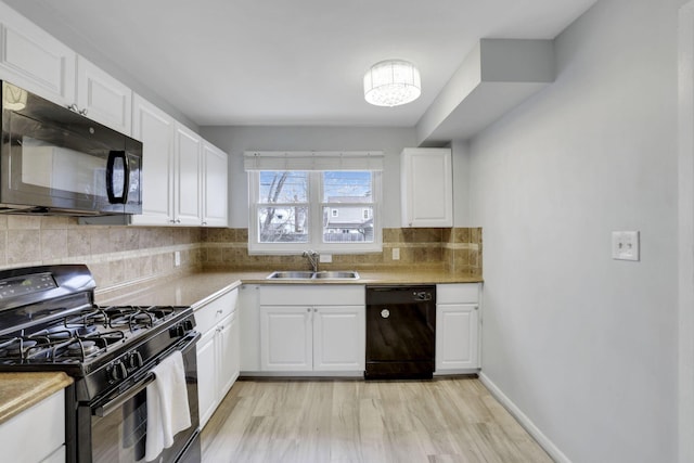 kitchen featuring decorative backsplash, white cabinets, a sink, and black appliances