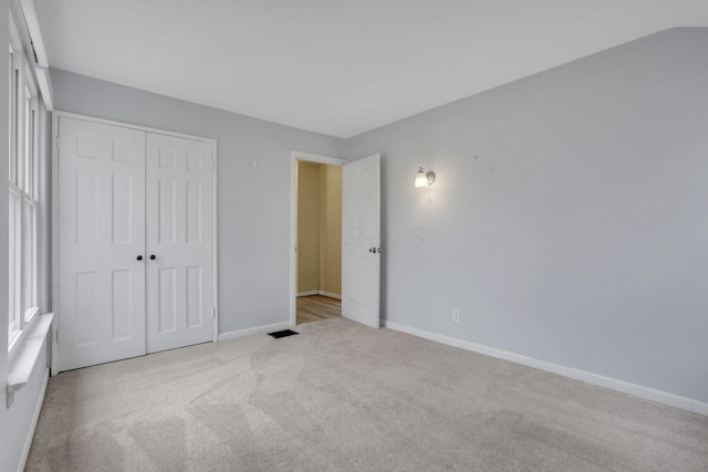 unfurnished bedroom with a closet, carpet flooring, visible vents, and baseboards