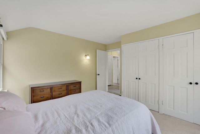 carpeted bedroom featuring vaulted ceiling and a closet