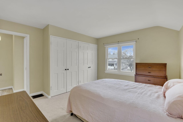 bedroom with carpet, a closet, visible vents, vaulted ceiling, and baseboards