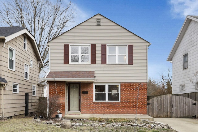 traditional-style house featuring fence and brick siding