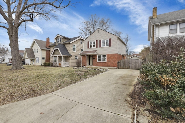 view of front of property with brick siding, a front lawn, and fence