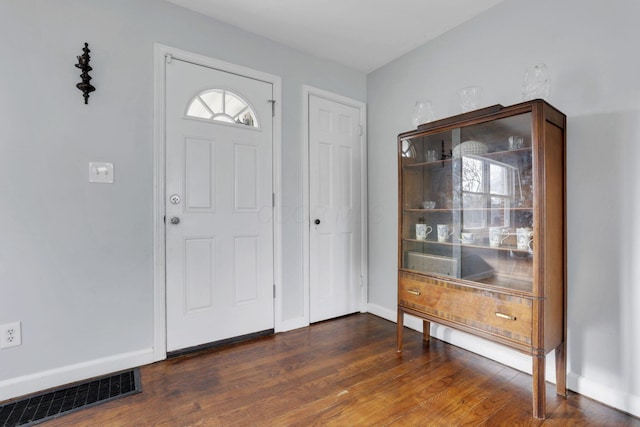 foyer featuring dark wood-type flooring, visible vents, and baseboards